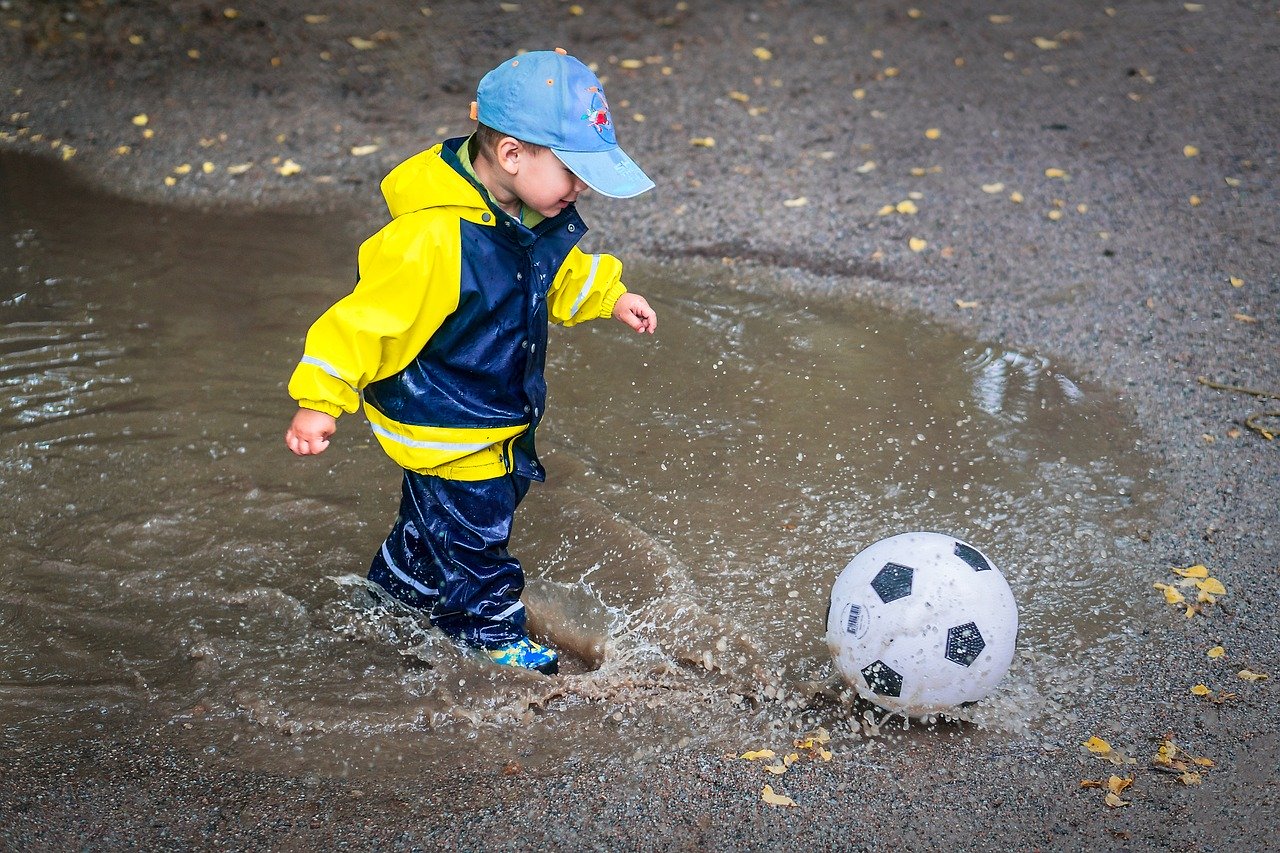 5 year old playing football in puddle