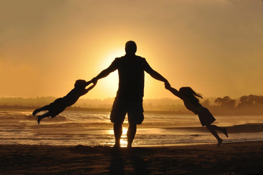 silhouette of dad swinging kids around