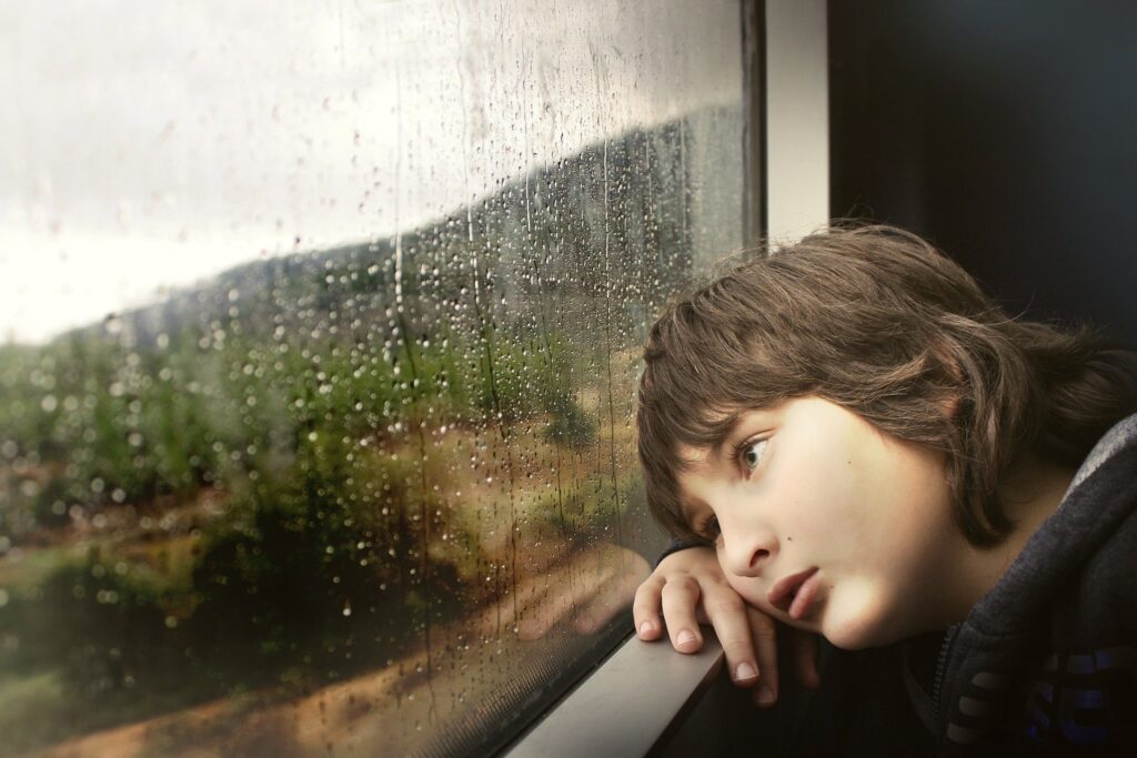 kid looking bored and staring out the window