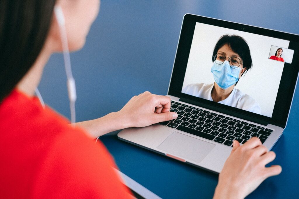 woman on laptop with doctor on sccreen