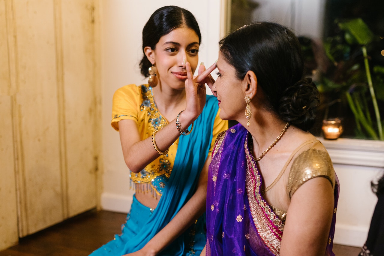 diwali celebrations. woman putting spot on another's forehead