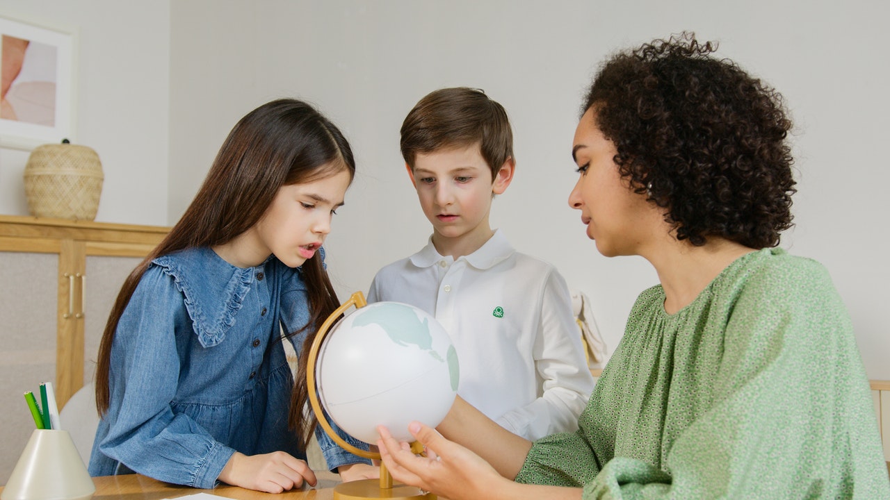 woman showing kids a globe