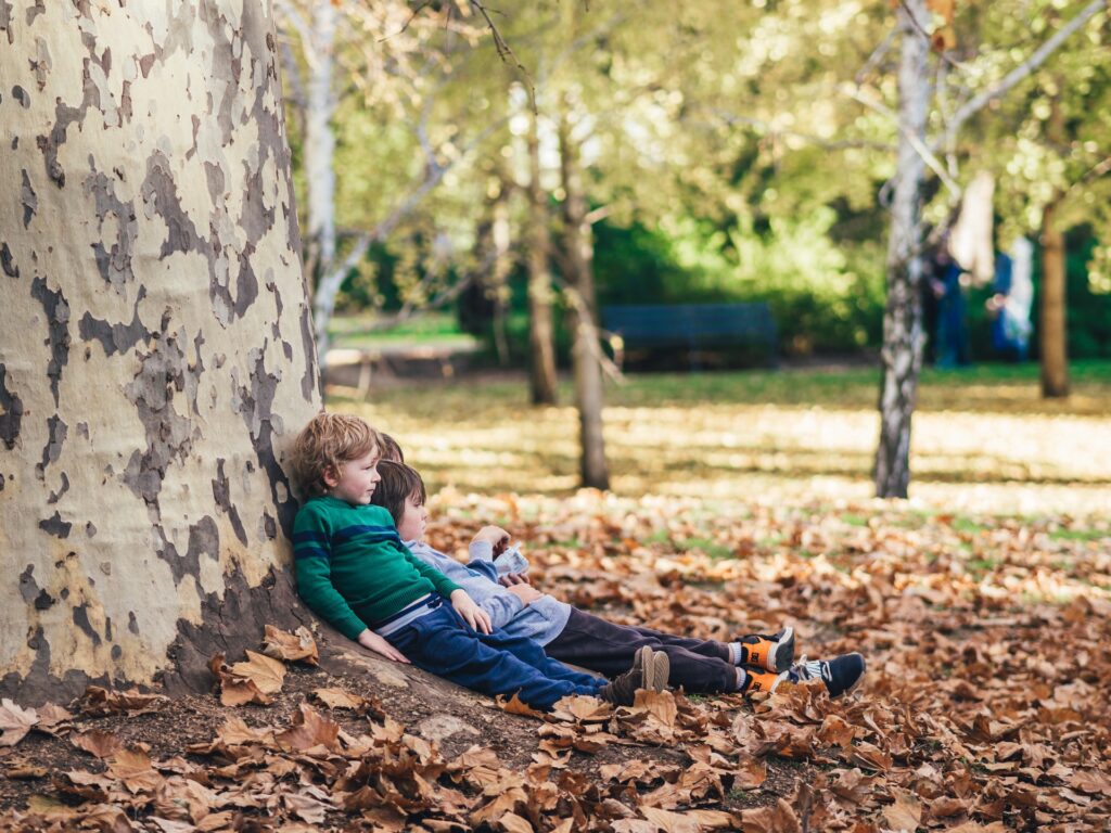 kids sitting against a tree