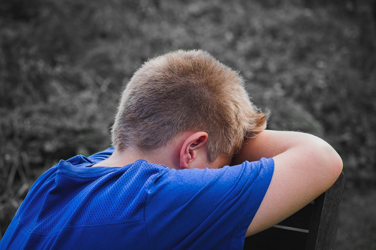 child with head in hands looking sad