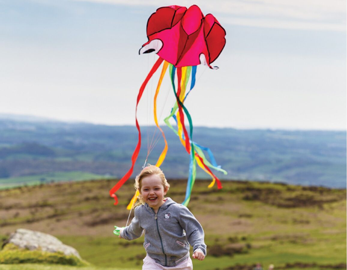 gifts for outdoorsy kids like this giant kite make for great pressies. There's a girl taking this one oer hills and vales