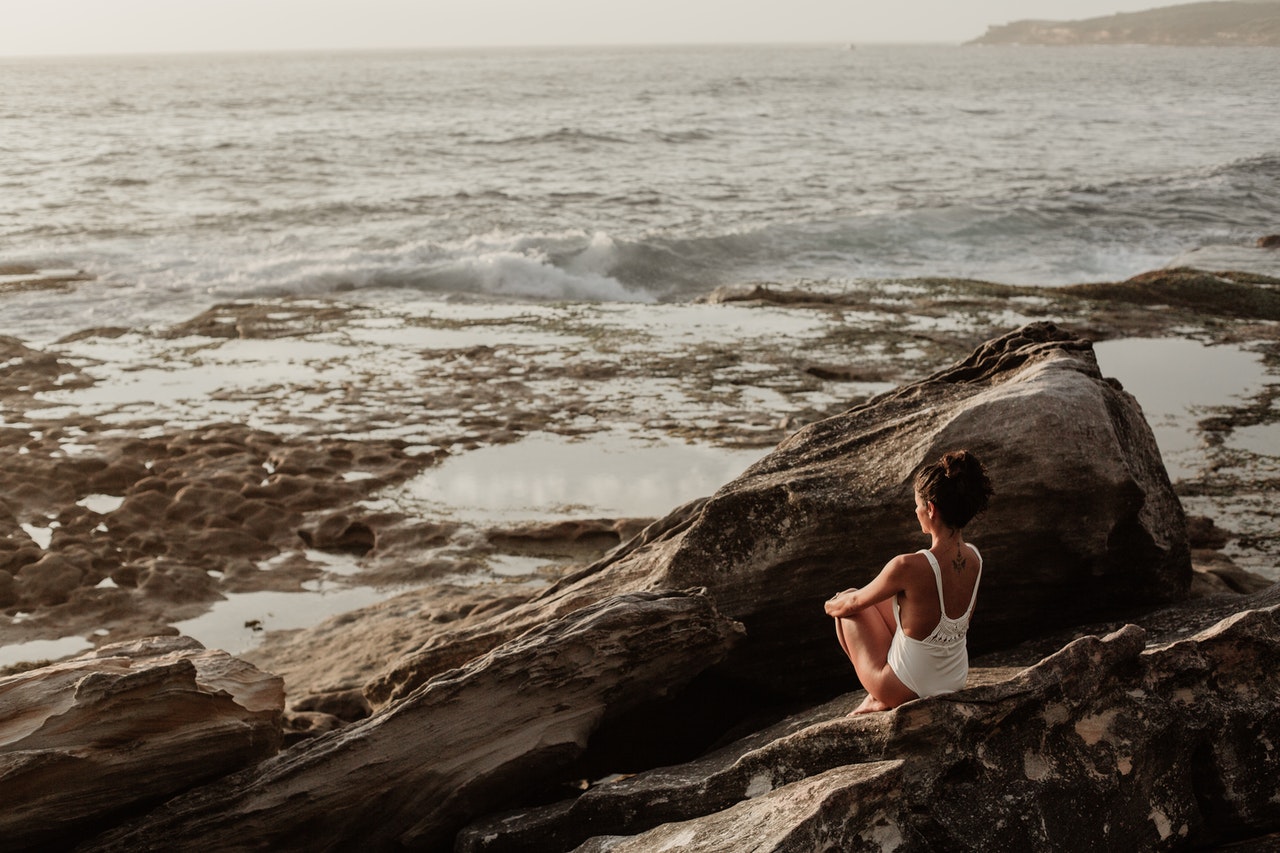 woman sat on rocky coast