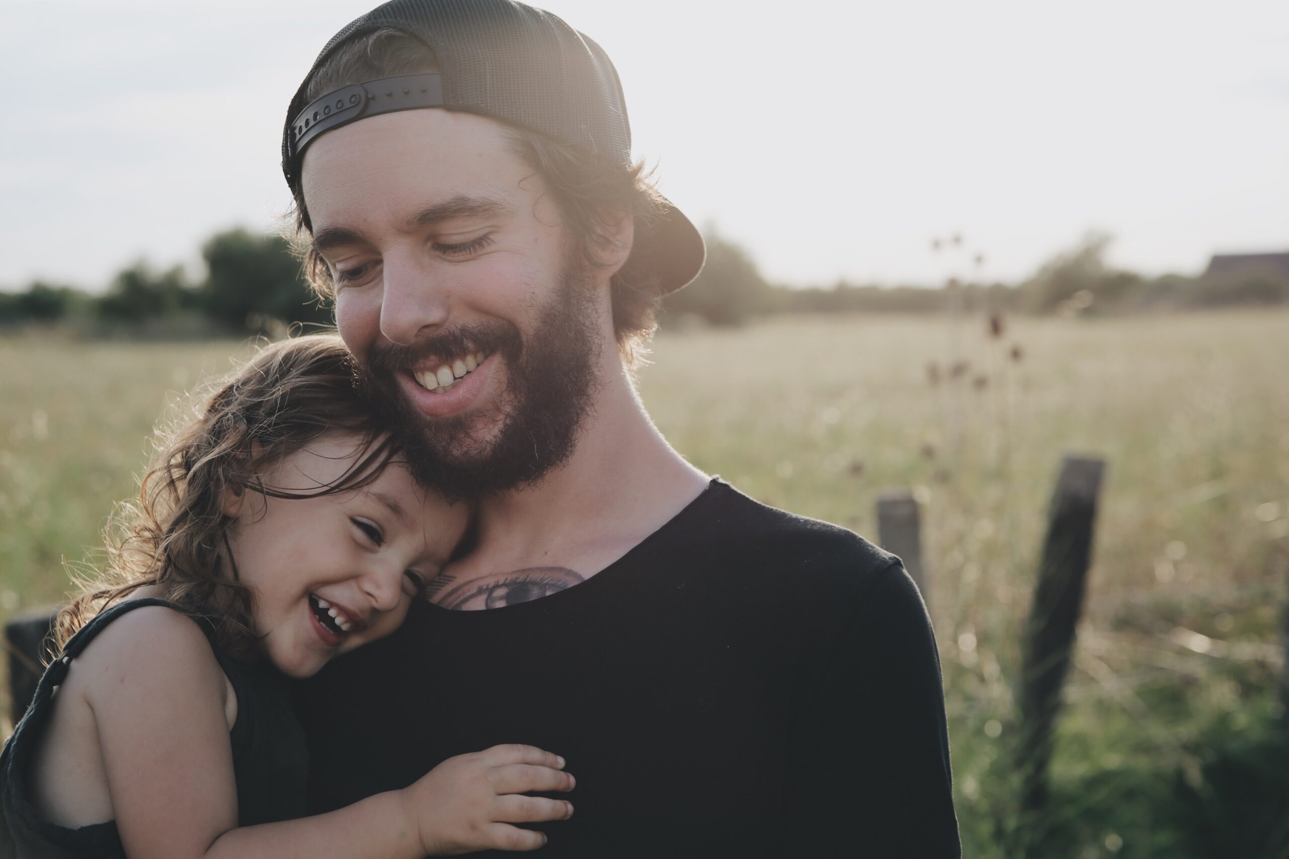 father hugging daughter in a field in sunshine