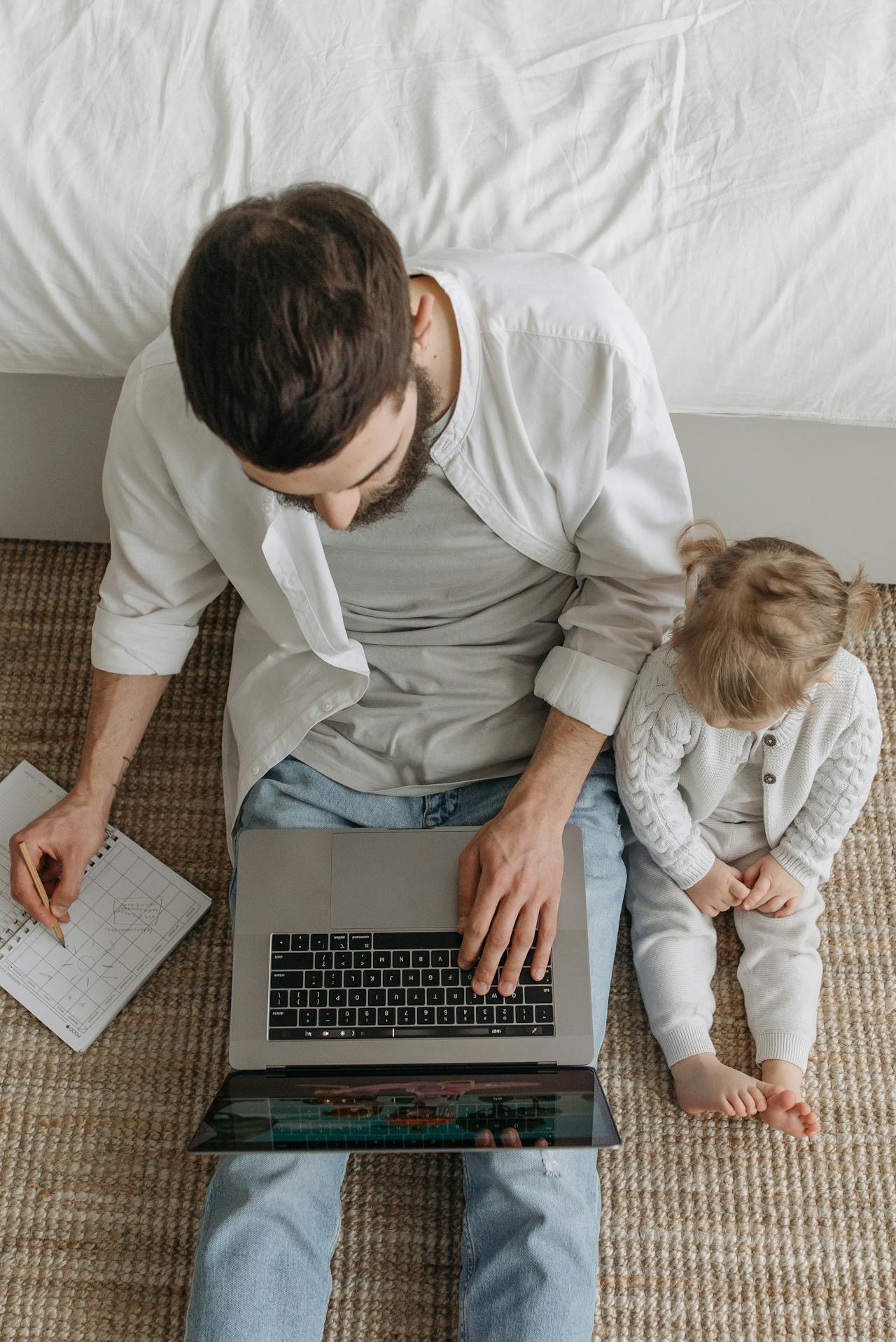 father using a laptop and toddler sat beside.
