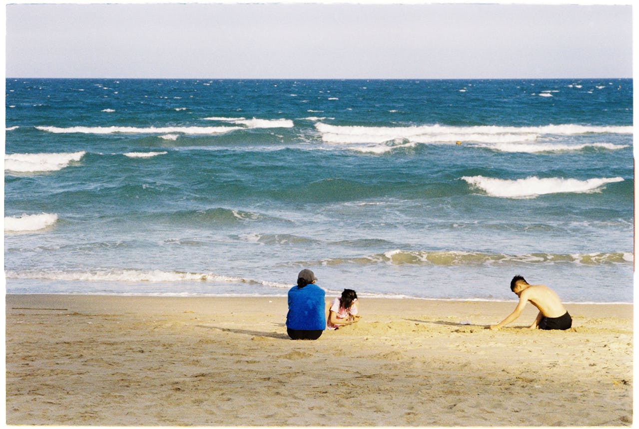 man watching his kids play on the beach.
