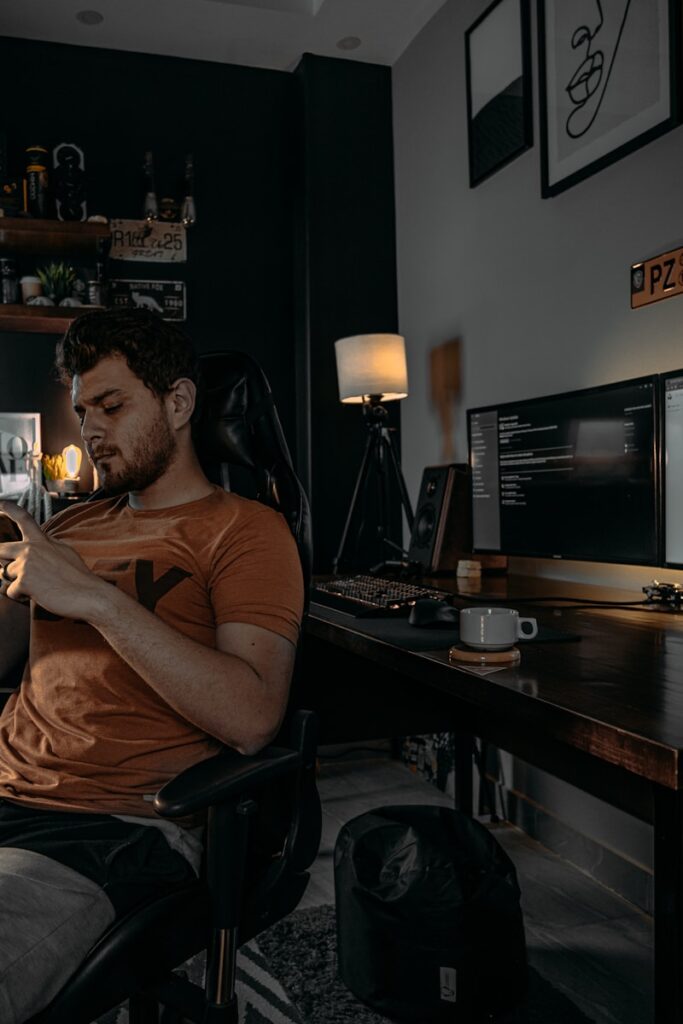 man in brown crew neck t-shirt sitting on black office rolling chair sitting in a man cave